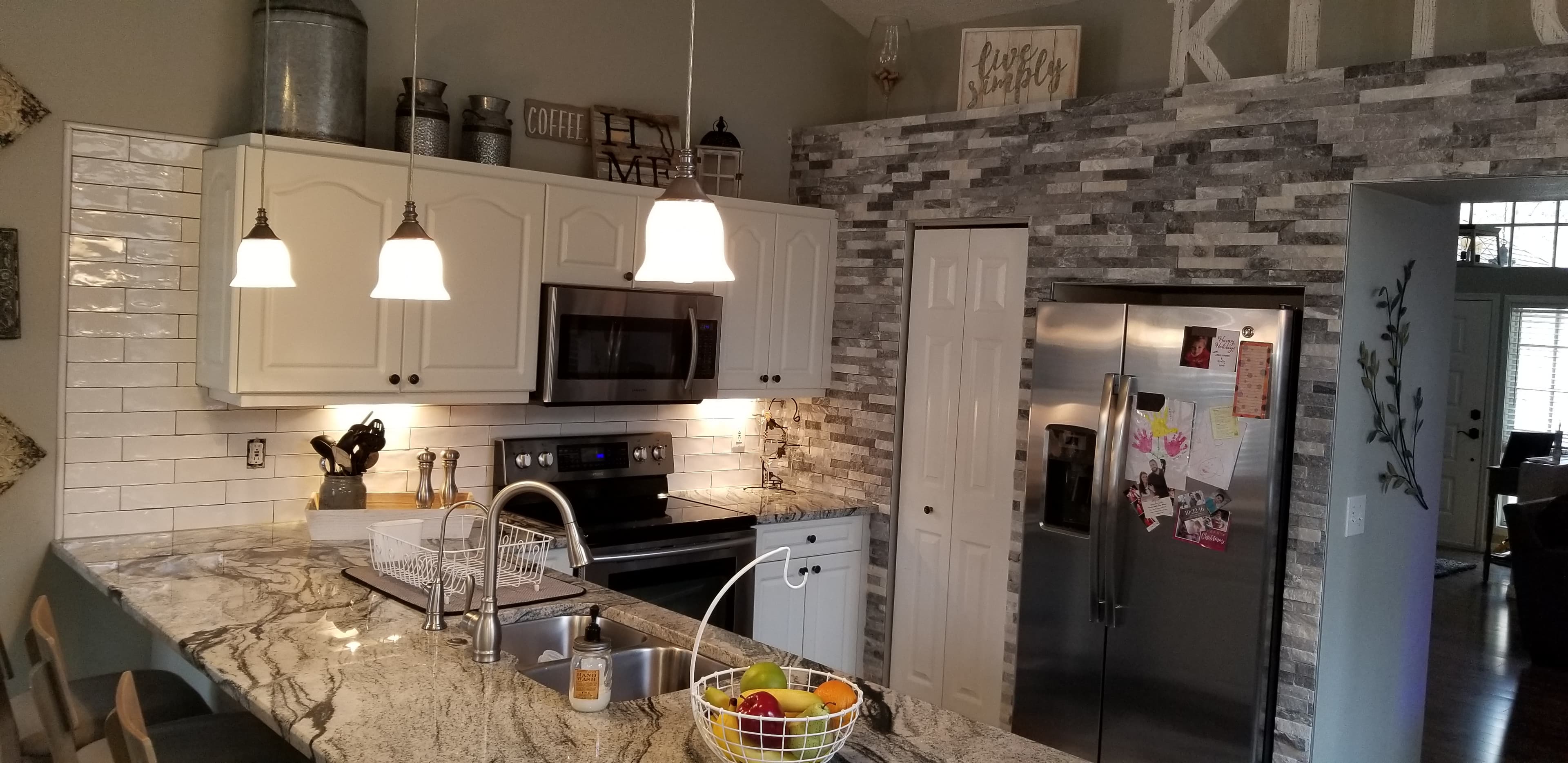 Farmhouse kitchen island with granite counters, pendant lighting, and stainless appliances