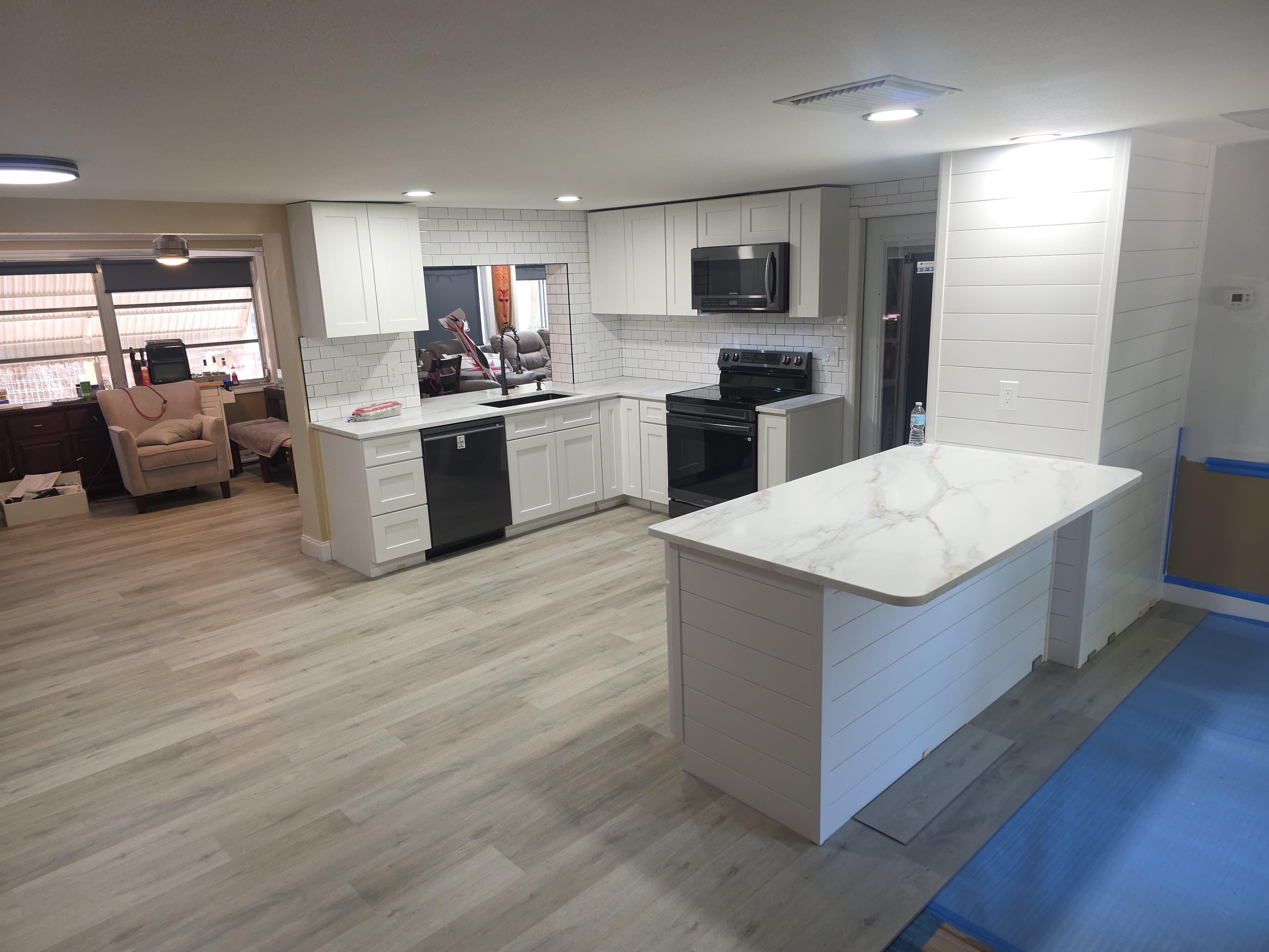 Renovated kitchen with white shaker cabinets, subway tile backsplash, quartz countertops, and shiplap peninsula
