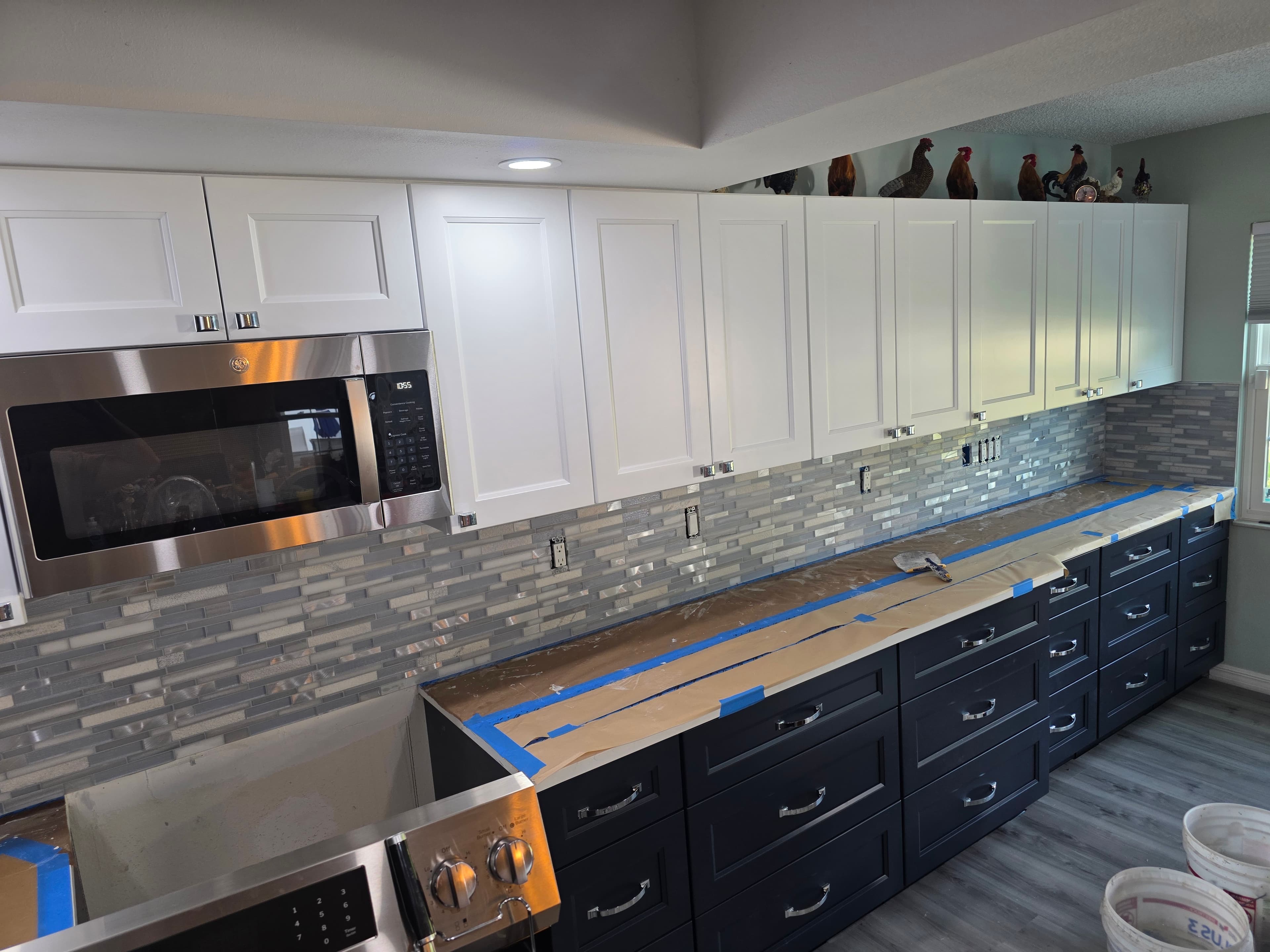 Two tone kitchen during cabinet installation with countertops covered for protection